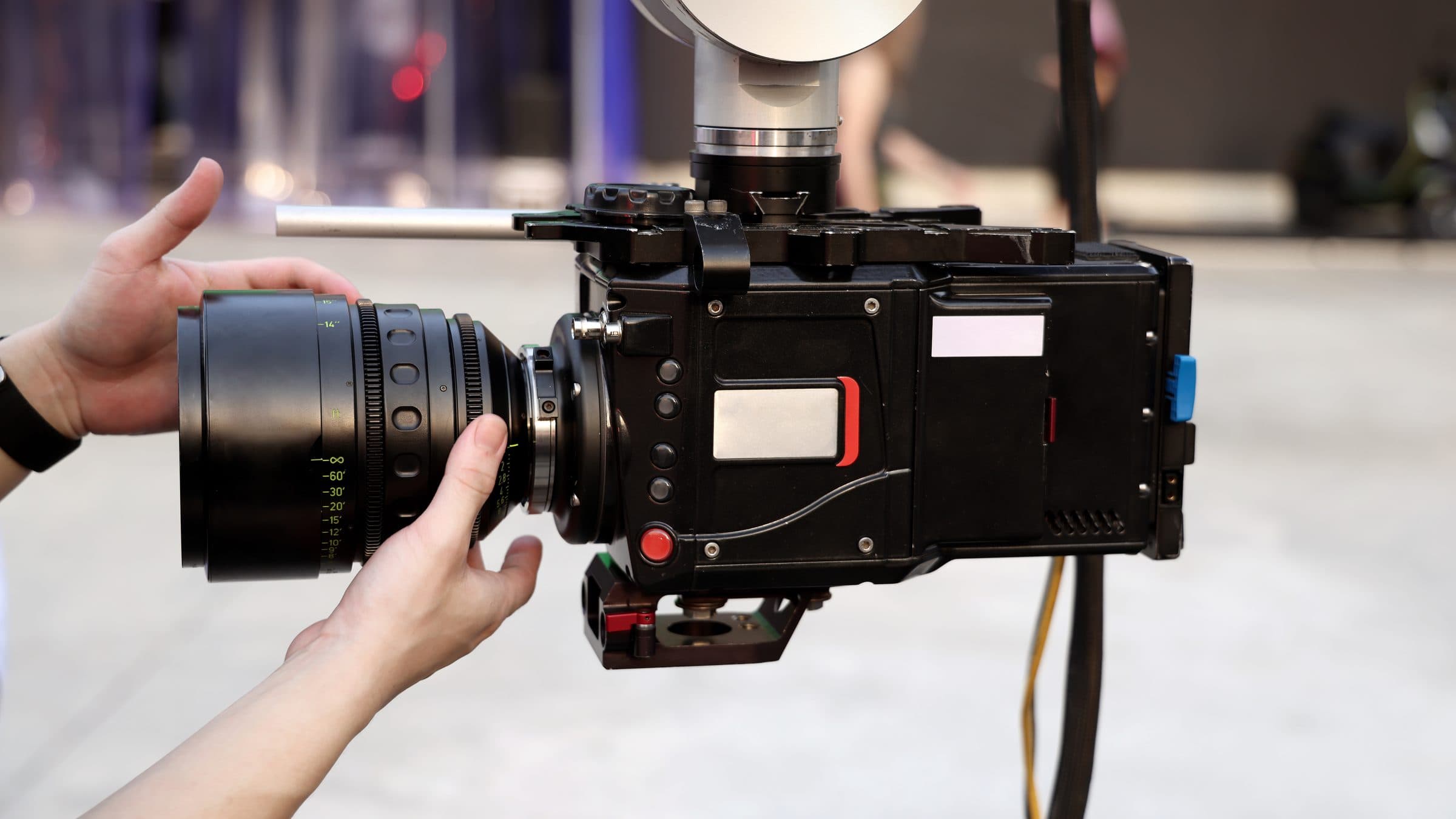 Hands mounting a cinema lens onto a camera body on set
